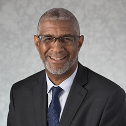 Portrait of man with graying hair, glasses, dark suit and tie